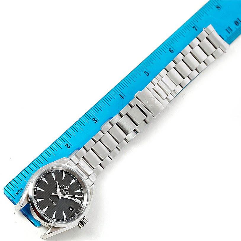 The image shows an Omega Aqua Terra 231.10.39.60.06.001 Men
s Stainless Steel Grey Dial 231.10.39.60.06.001 Men
s Stainless Steel Grey Dial watch laid next to a blue ruler, highlighting the face and metal bracelet.