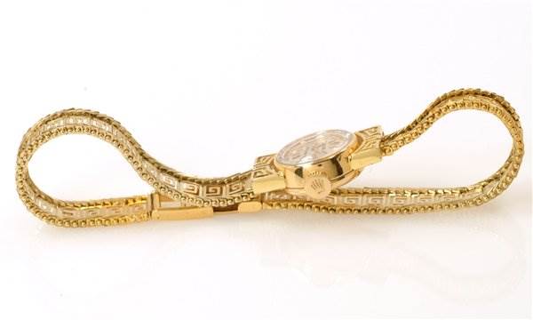 This is a side view of a Rolex Cocktail 2113 Women's Yellow Gold Silver Dial 2113 Women's Yellow Gold Silver Dial model watch, showing its gold band and case with intricate detailing.