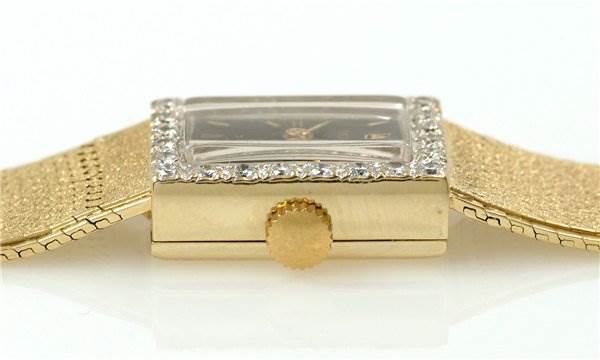 The image shows a side view of a Rolex Cocktail Women's Yellow Gold Black Dial Women's Yellow Gold Black Dial model watch, highlighting its crown, case, and part of the band.