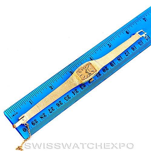 The image shows a Rolex Cocktail 8422 Women's Yellow Gold Champagne Dial 8422 Women's Yellow Gold Champagne Dial model watch laid flat alongside a blue ruler, highlighting its length and golden design.