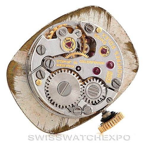 The image shows the movement mechanism of a Rolex Cocktail Women's Yellow Gold Silver Dial Women's Yellow Gold Silver Dial model watch, highlighting gears and intricate internal components.