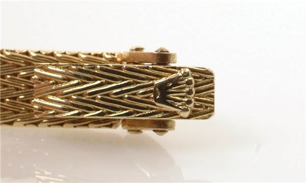 The image shows a close-up view of the clasp of the Rolex Cocktail 8415 Women's Yellow Gold Champagne Dial 8415 Women's Yellow Gold Champagne Dial model watch, highlighting its gold textured design and the Rolex logo.