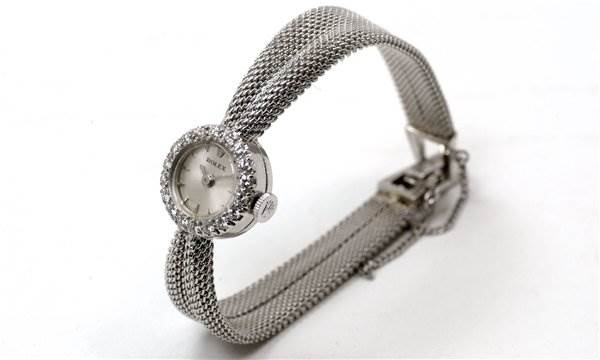 The image shows a side view of a Rolex Cocktail Women's White Gold Silver Dial Women's White Gold Silver Dial model watch, featuring its mesh band and jeweled bezel.