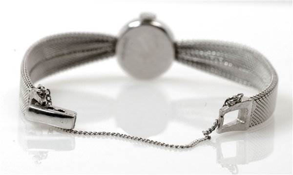 The image shows the back of the Rolex Cocktail Women's White Gold Silver Dial Women's White Gold Silver Dial watch, highlighting its clasp and safety chain from a rear angle.