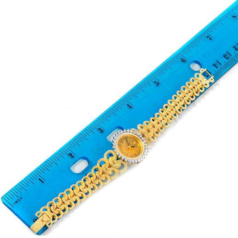 The image shows a top view of a Rolex Cocktail 8312 Women's Yellow Gold Champagne Dial 8312 Women's Yellow Gold Champagne Dial model watch with its golden band placed alongside a blue ruler for scale.