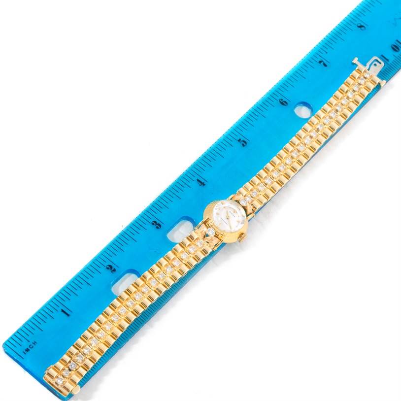 The image shows a Rolex Cocktail 8271 Women's Yellow Gold Silver Dial 8271 Women's Yellow Gold Silver Dial model watch laid horizontally next to a blue ruler, displaying the face and strap.