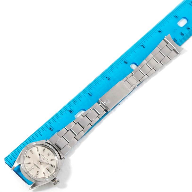 The Rolex Vintage Collection 1501 Men's Stainless Steel Silver Dial 1501 Men's Stainless Steel Silver Dial watch is shown from an overhead angle, displaying its face, bracelet, and clasp alongside a blue ruler.