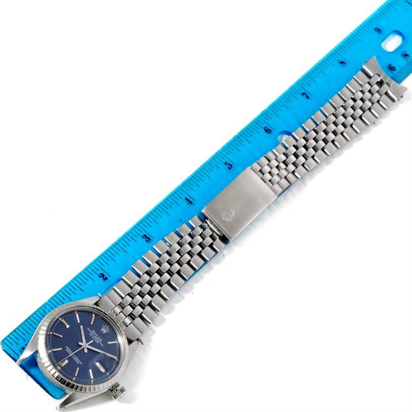 The Rolex Vintage Collection 1603 Men's Stainless Steel Blue Dial 1603 Men's Stainless Steel Blue Dial watch is shown from an overhead angle, displaying the face, bracelet, and clasp alongside a blue ruler.