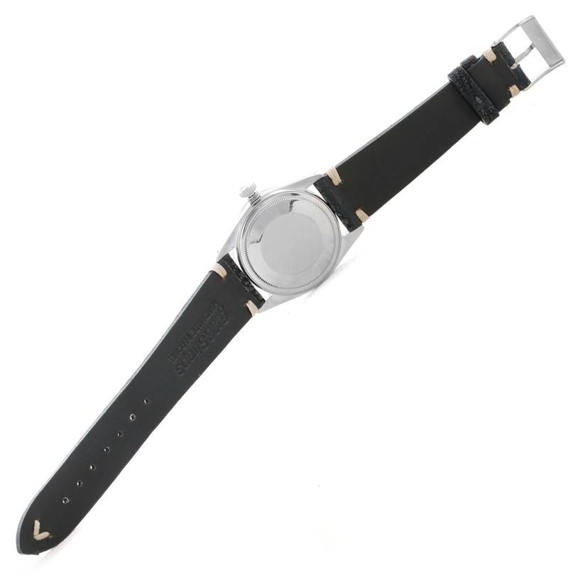 This image shows the back side of a Vintage Collection Rolex watch with a black leather strap and silver buckle, at a slightly tilted angle.