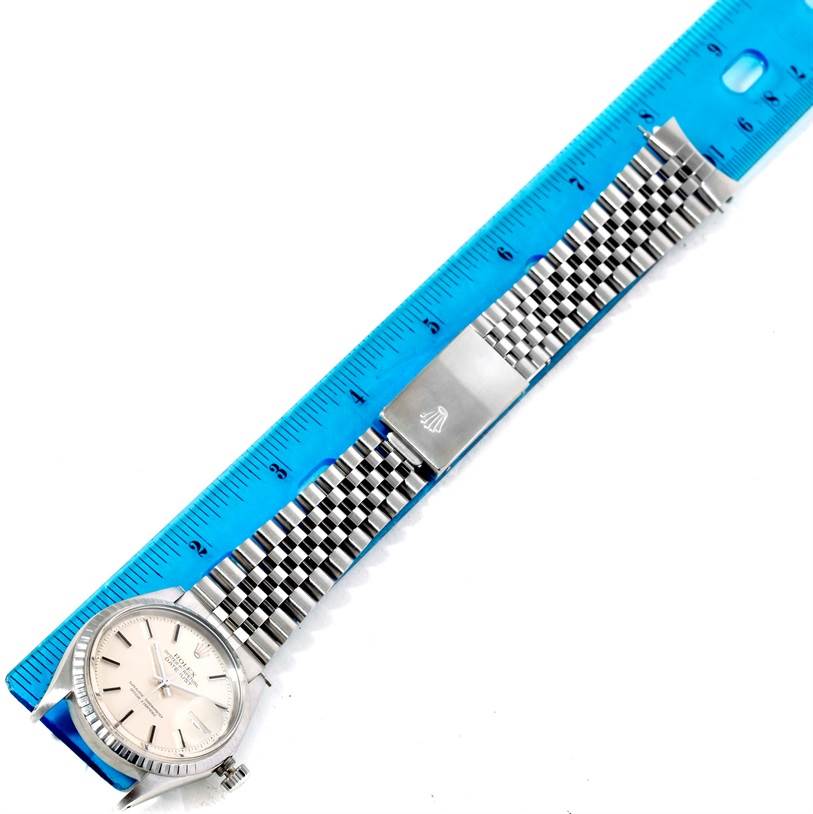 The Rolex Vintage Collection 1603 Men's Stainless Steel Silver Dial 1603 Men's Stainless Steel Silver Dial watch is shown from above, displaying its face, bracelet, and clasp alongside a blue ruler.