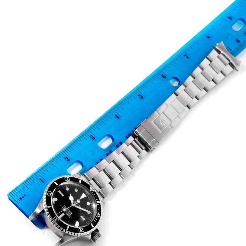 The image shows a Rolex Vintage Collection 1665 Men's Stainless Steel Black Dial 1665 Men's Stainless Steel Black Dial watch laid alongside a ruler, highlighting its bracelet and face from a top-down angle.