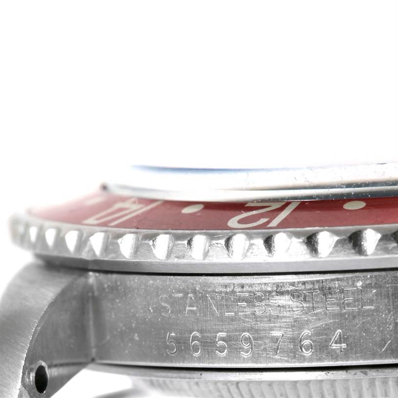 The image shows a close-up side view of a Rolex Vintage Collection 1675 Men's Stainless Steel Black Dial 1675 Men's Stainless Steel Black Dial watch, highlighting its red bezel and part of its case with serial number.