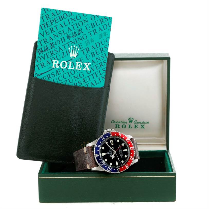 The Rolex Vintage Collection 1675 Men's Stainless Steel Black Dial 1675 Men's Stainless Steel Black Dial watch is displayed front-facing inside an open green box, accompanied by its documentation.