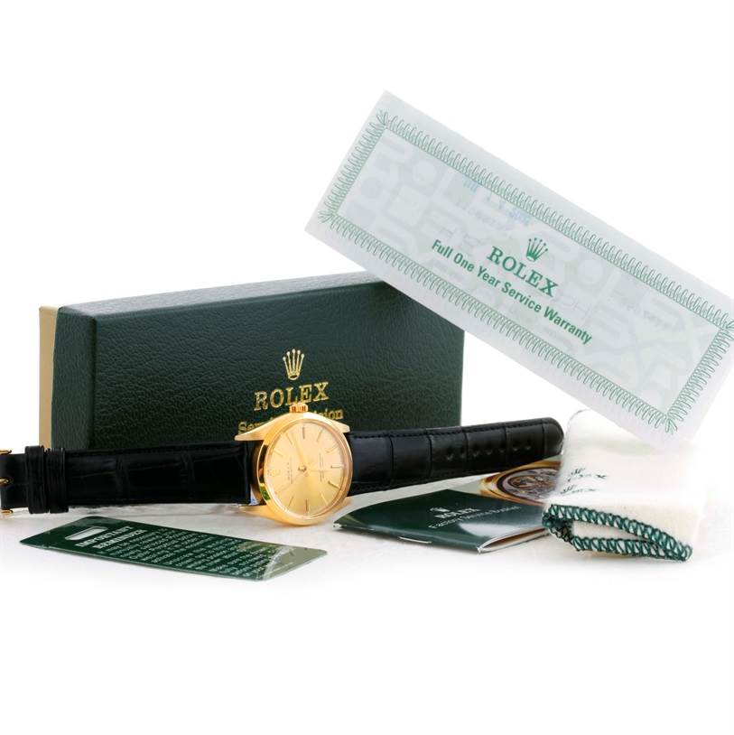 The image shows the Rolex Vintage Collection 1002 Men's Yellow Gold Champagne Dial 1002 Men's Yellow Gold Champagne Dial watch with a black strap, warranty, box, and documentation from a front angle.