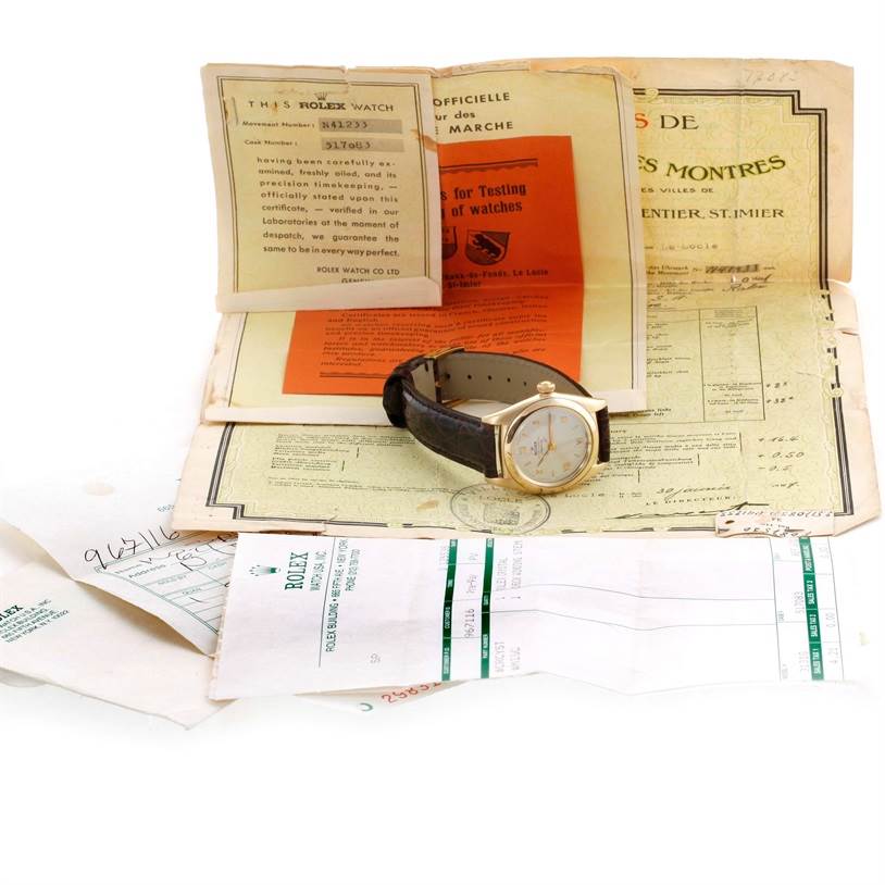 The image shows a Rolex Vintage Collection 3131G Men's Yellow Gold Silver Dial 3131G Men's Yellow Gold Silver Dial watch, facing upward, with accompanying documents laid out behind it.