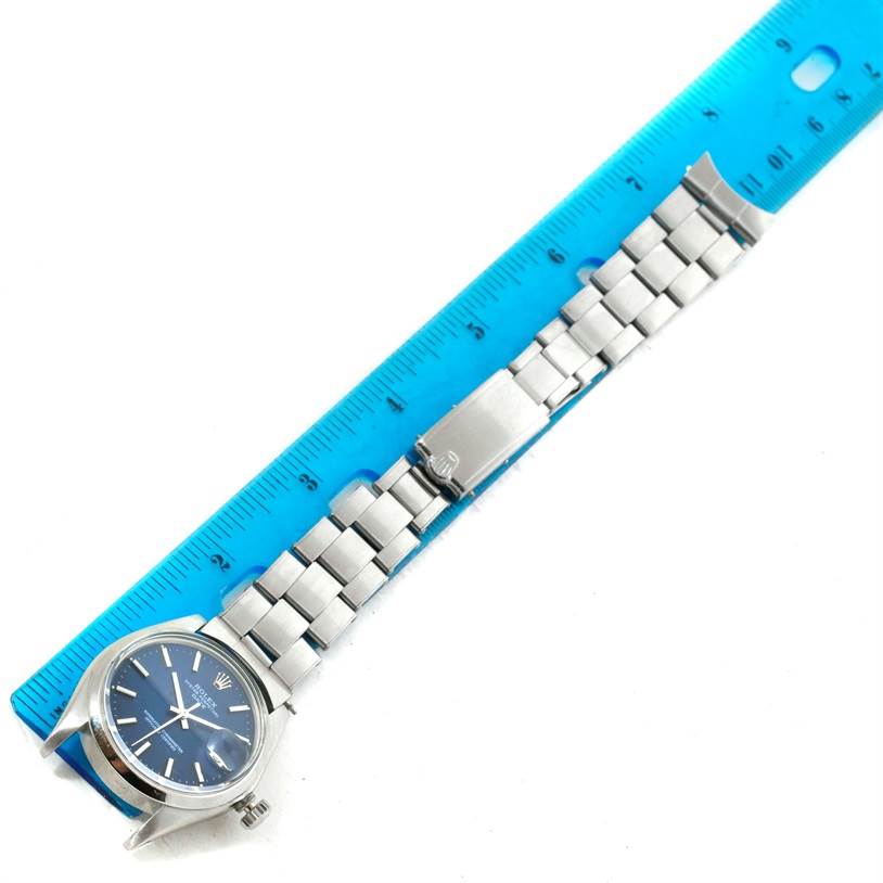 The image shows a Rolex Vintage Collection 1500 Men's Stainless Steel Blue Dial 1500 Men's Stainless Steel Blue Dial watch laid flat next to a blue ruler, displaying the watch face, bracelet, and clasp.