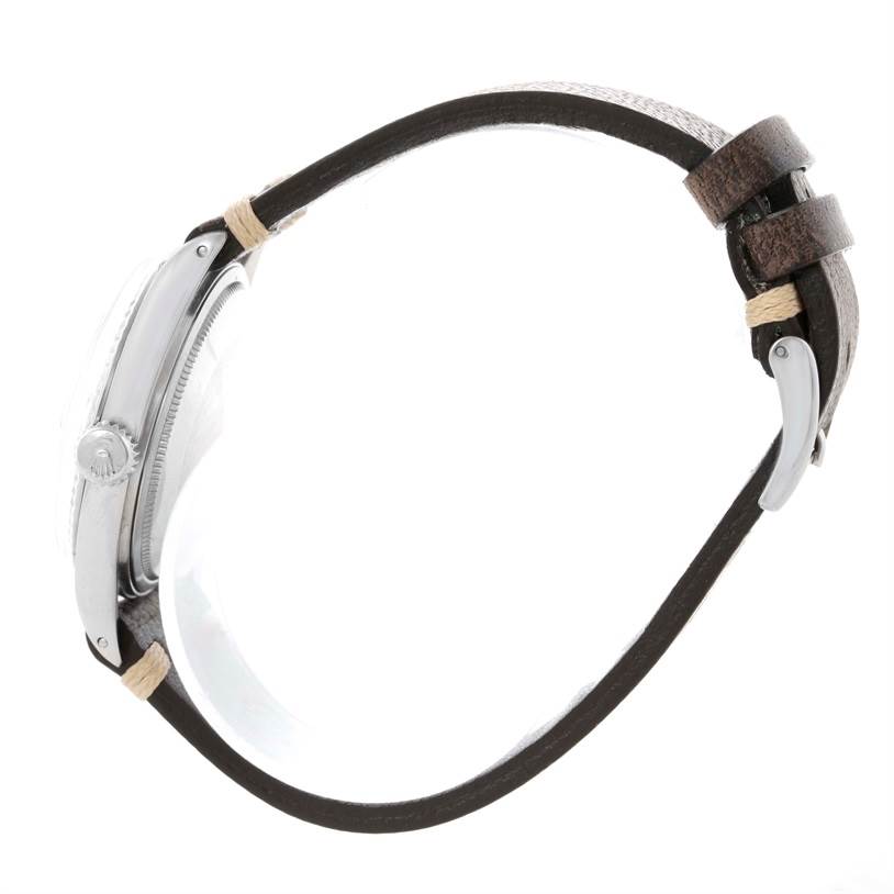 This side view of the Rolex Vintage Collection 1601 Men's Stainless Steel Silver Dial 1601 Men's Stainless Steel Silver Dial watch shows its crown, case, and leather strap with buckle.