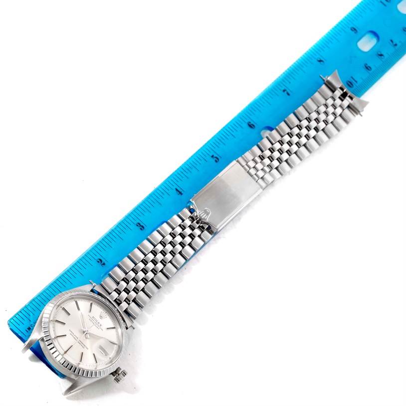 The image shows the Rolex Vintage Collection 1603 Men's Stainless Steel Silver Dial 1603 Men's Stainless Steel Silver Dial model from a top view, with the watch face and metal strap laid next to a blue ruler.