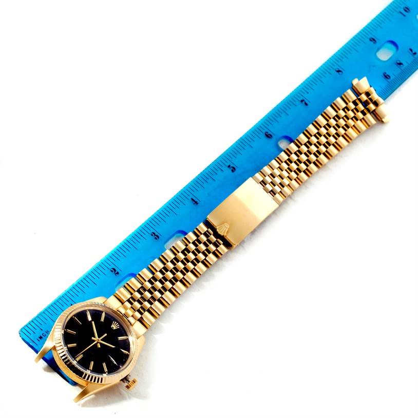 The Rolex Vintage Collection 15037 Men's Yellow Gold Black Dial 15037 Men's Yellow Gold Black Dial watch is shown from a top view, with focus on the black dial, gold bezel, and bracelet next to a ruler.