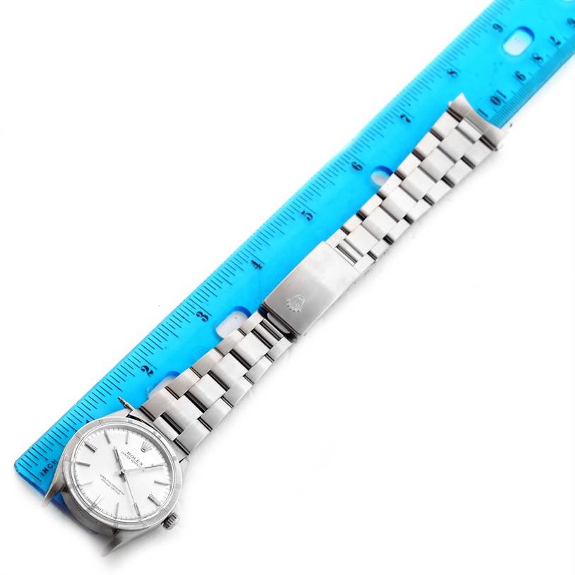 The image shows a Rolex Vintage Collection 1007 Men's Stainless Steel Silver Dial 1007 Men's Stainless Steel Silver Dial watch lying flat next to a blue ruler, displaying its face, bracelet, and clasp.