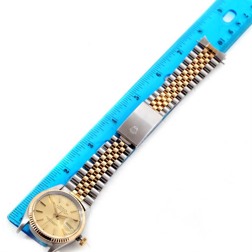 This image shows a top view of a Rolex Vintage Collection 16013 Men
s Stainless Steel Champagne Dial 16013 Men
s Stainless Steel Champagne Dial watch, including its face and two-tone metal bracelet, next to a ruler.