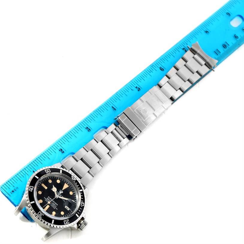 The image shows a top view of a Rolex Vintage Collection 1680 Men's Stainless Steel Black Dial 1680 Men's Stainless Steel Black Dial watch with a metal band and a blue ruler for scale.