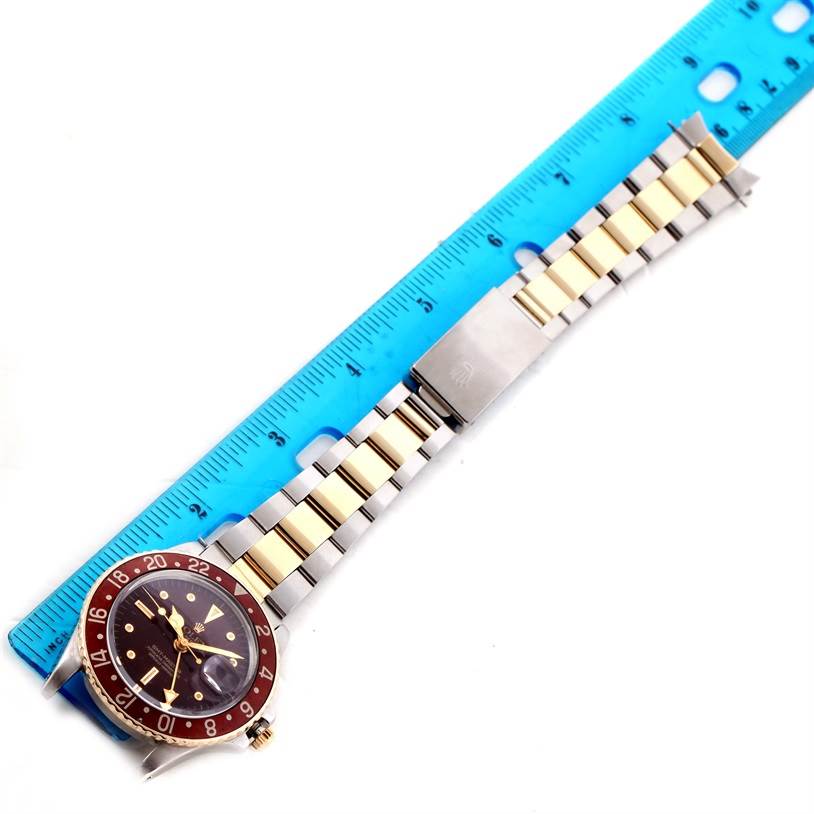 The Vintage Collection Rolex watch is shown from a top-down angle, including the watch face and two-tone band next to a ruler.