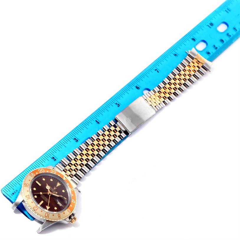 The image shows a Rolex Vintage Collection 16753 Men's Stainless Steel Brown Dial 16753 Men's Stainless Steel Brown Dial watch placed next to a blue ruler, displaying the face and bracelet.