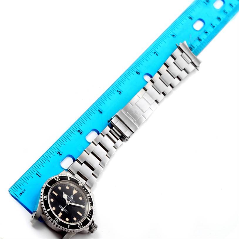 The image shows a Rolex Vintage Collection 5513 Men's Black Dial 5513 Men's Black Dial watch laid flat with its band extended alongside a blue ruler for measurement.