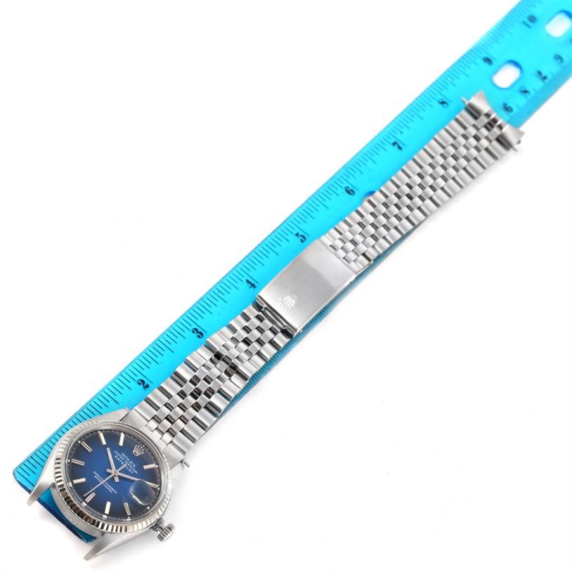 The Vintage Collection Rolex watch, shown from a top-down angle, features the face, bezel, and full bracelet next to a blue ruler.