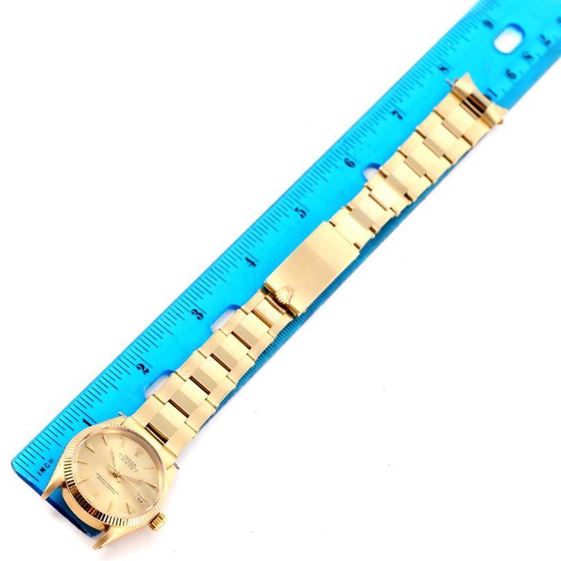 The Vintage Collection Rolex watch is shown from an overhead angle, displaying its dial, bracelet, and clasp next to a blue ruler.