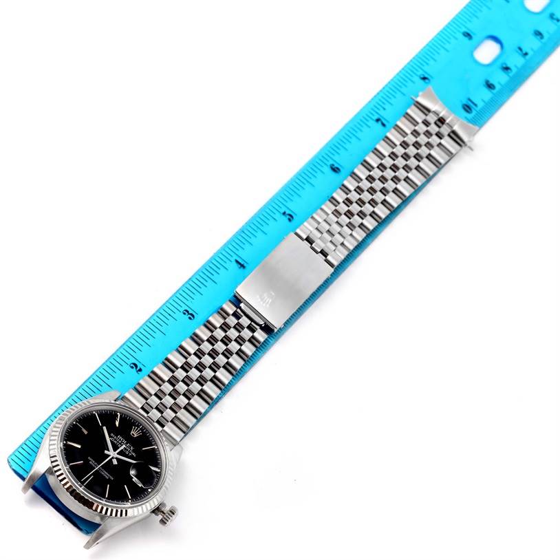 This image shows a top-down view of the Rolex Vintage Collection 16014 Men's Stainless Steel Black Dial 16014 Men's Stainless Steel Black Dial watch with a ruler and focus on its band and clasp.