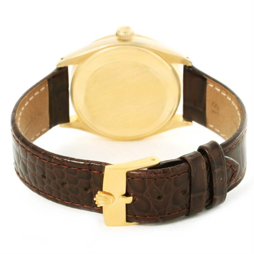 The image shows the back view of a Rolex Vintage Collection 6569 Men's Yellow Gold Brown Dial 6569 Men's Yellow Gold Brown Dial watch with its brown leather strap and gold clasp.