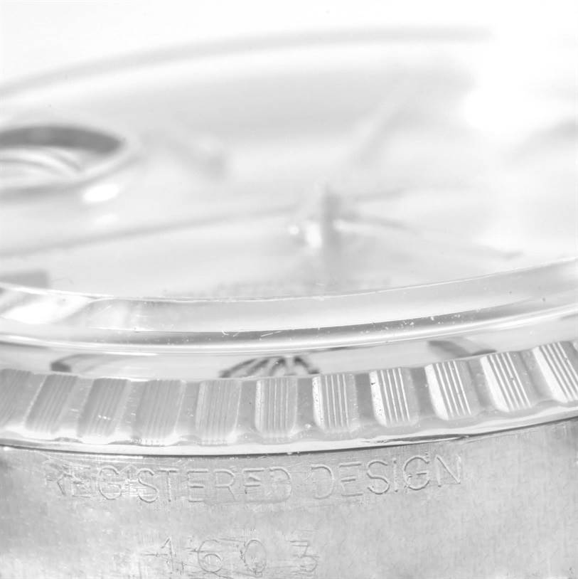 This side view of the Rolex Vintage Collection 1603 Men's Stainless Steel Silver Dial 1603 Men's Stainless Steel Silver Dial watch displays the bezel and part of the case with "Registered Design" etching.