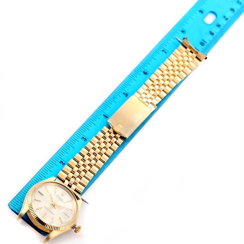 The image shows a Rolex Vintage Collection 1503 Men's Yellow Gold Silver Dial 1503 Men's Yellow Gold Silver Dial watch laid flat with its gold bracelet alongside a blue ruler.