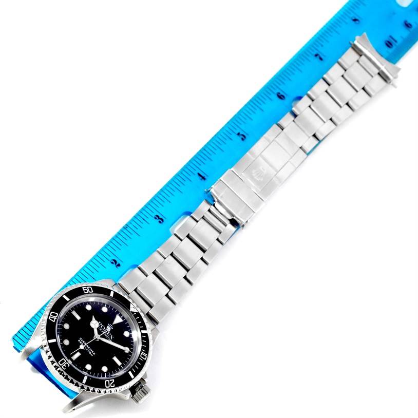 The image shows a Rolex Vintage Collection 5513 Men's Stainless Steel Black Dial 5513 Men's Stainless Steel Black Dial watch laid flat beside a blue ruler, displaying its face and metal bracelet.