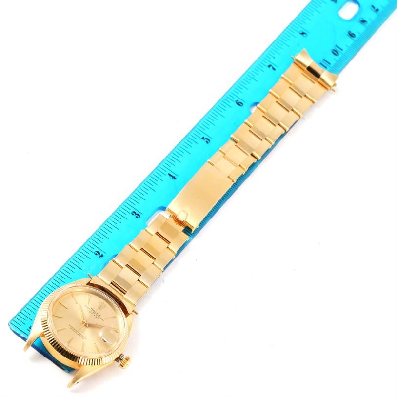 The Vintage Collection Rolex watch is shown laid flat, highlighting its gold case, dial, and metal bracelet alongside a blue ruler for scale.