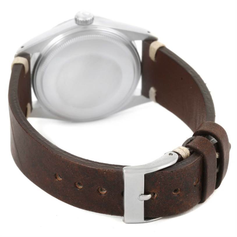 The image shows the back of a Vintage Collection Rolex watch with a brown leather strap and silver buckle.