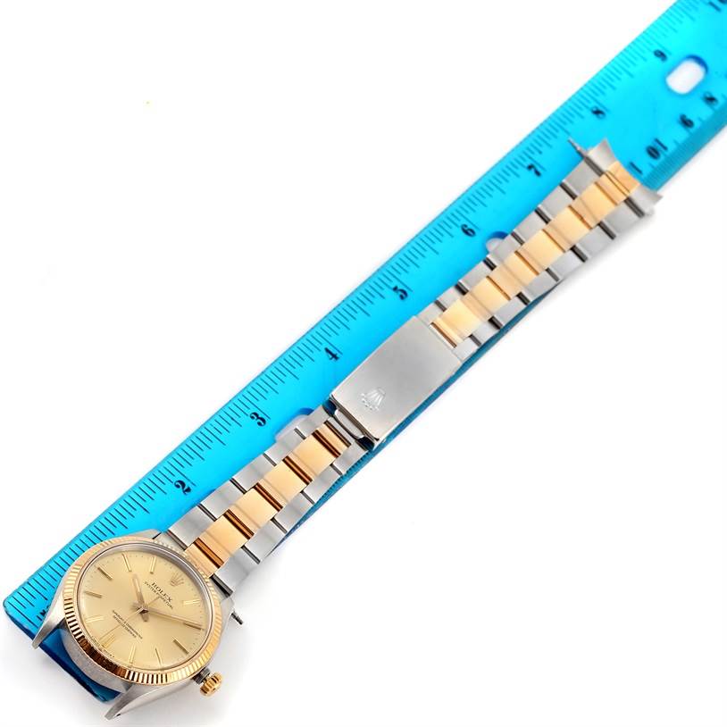 The image shows a Rolex Vintage Collection 1005 Men's Steel and Gold (two tone) Champagne Dial 1005 Men's Steel and Gold (two tone) Champagne Dial watch laid flat next to a blue ruler, displaying its gold and silver bracelet.