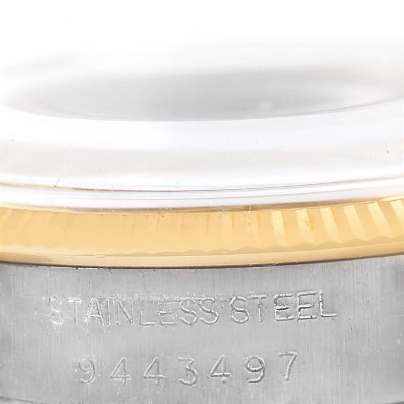 This close-up image of the Rolex Vintage Collection 1005 Men's Steel and Gold (two tone) Champagne Dial 1005 Men's Steel and Gold (two tone) Champagne Dial watch shows part of the fluted bezel and the "Stainless Steel" engraving with a serial number.