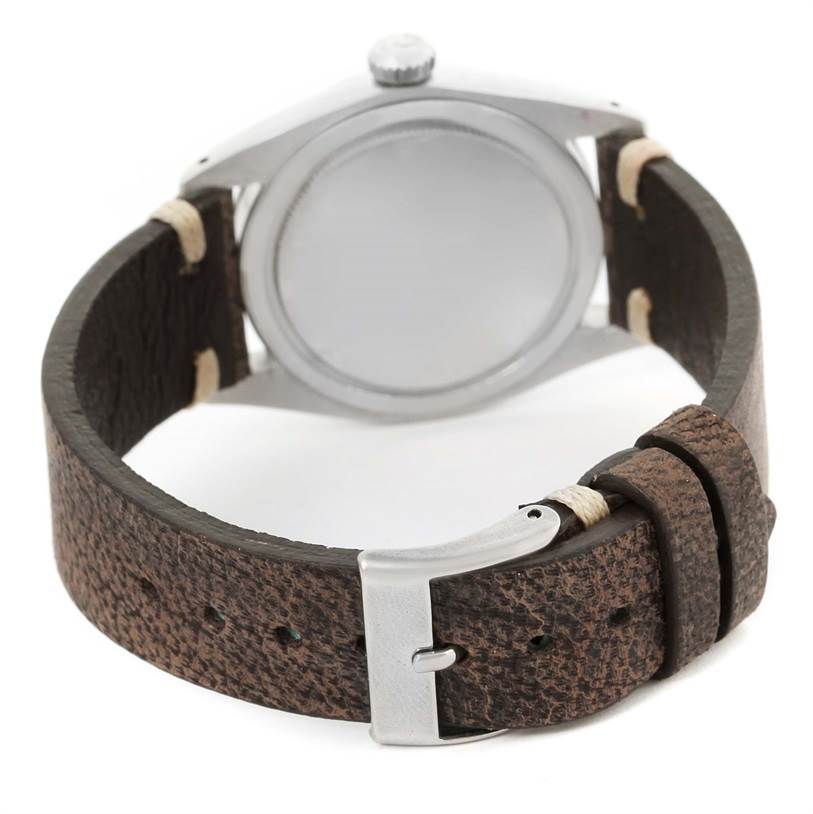 This image shows the backside of the Rolex Vintage Collection 6427 Men's Stainless Steel Silver Dial 6427 Men's Stainless Steel Silver Dial watch, highlighting the case back and brown leather strap with a buckle.