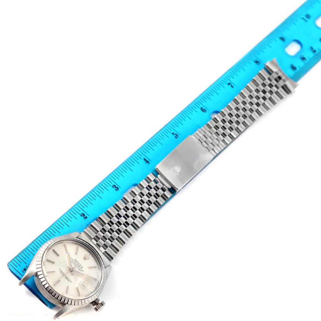 This image shows a side angle view of the Rolex Vintage Collection 16030 Men's Stainless Steel Silver Dial 16030 Men's Stainless Steel Silver Dial watch with a focus on its face, bracelet, and clasp next to a blue ruler.