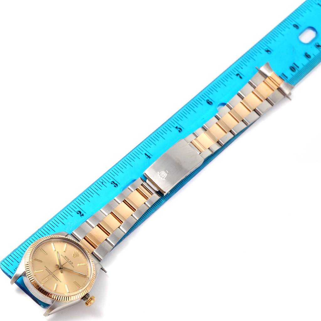 The image shows a Rolex Vintage Collection 1005 Men's Steel and Gold (two tone) Champagne Dial 1005 Men's Steel and Gold (two tone) Champagne Dial watch laid flat next to a blue ruler, displaying the face and two-tone metal strap.