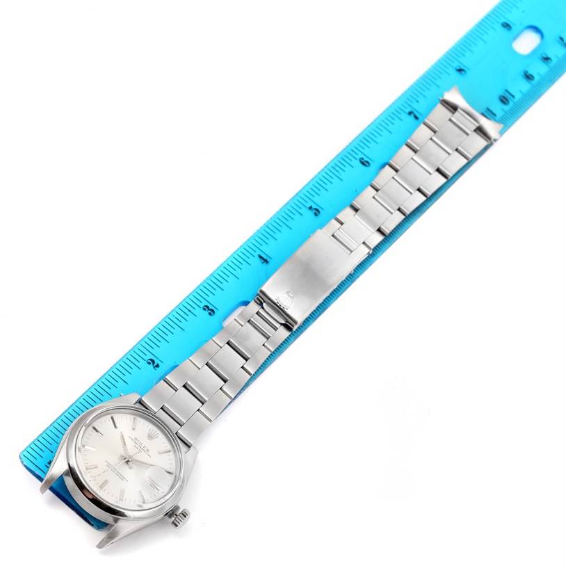 The Rolex Vintage Collection 1500 Men's Stainless Steel Silver Dial 1500 Men's Stainless Steel Silver Dial model watch is shown from a top-down angle, displaying the face, bracelet, and clasp against a blue ruler.