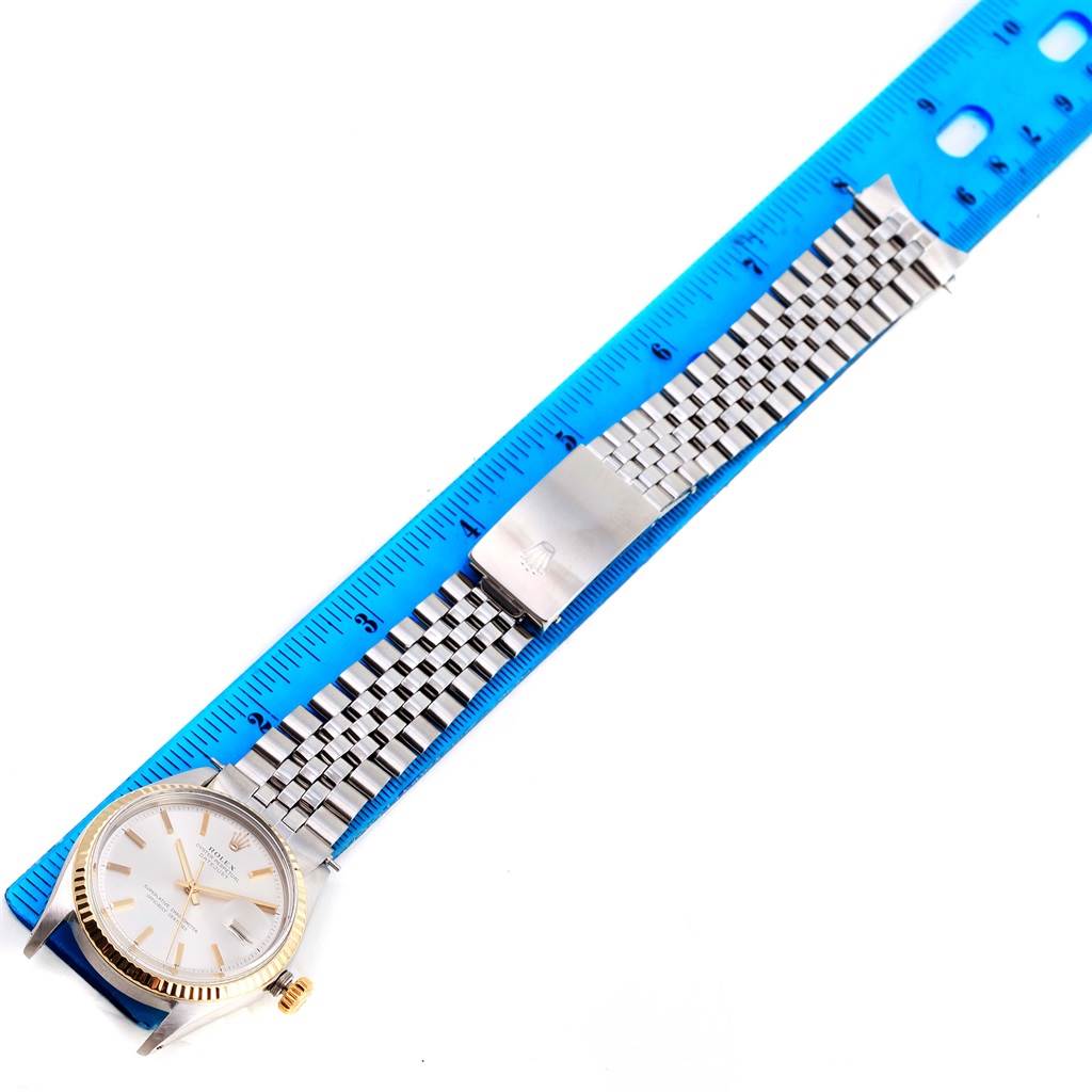 The image shows a top-down view of the Rolex Vintage Collection 1601 Men's Stainless Steel Silver Dial 1601 Men's Stainless Steel Silver Dial watch, displaying its face, bracelet, and clasp next to a blue ruler.