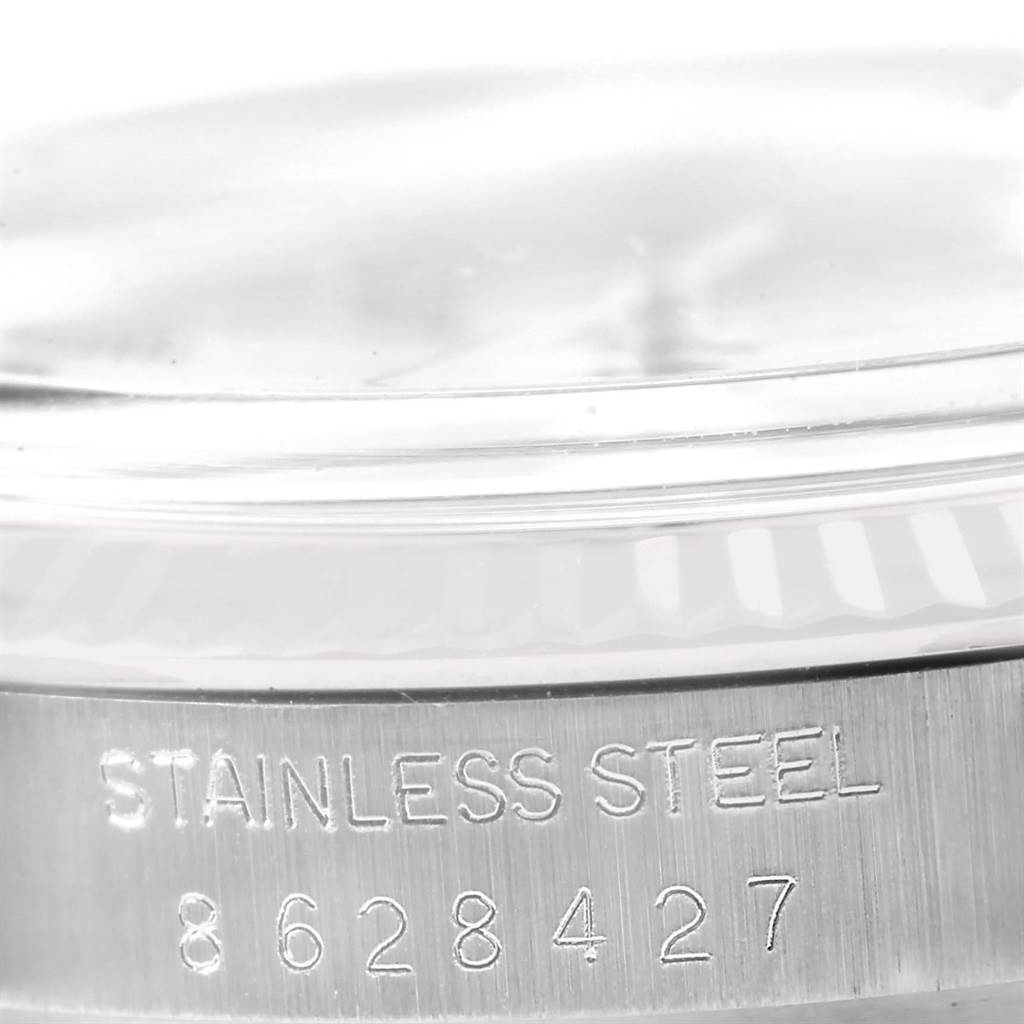 The image shows a close-up of the side of a Rolex Vintage Collection 16014 Men's Stainless Steel Silver Dial 16014 Men's Stainless Steel Silver Dial watch with "Stainless Steel" and its serial number engraved.