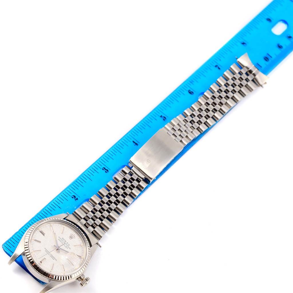 The image shows a Rolex Vintage Collection 16014 Men's Stainless Steel Silver Dial 16014 Men's Stainless Steel Silver Dial watch with a metal bracelet, clasp, and dial face, positioned alongside a blue ruler.