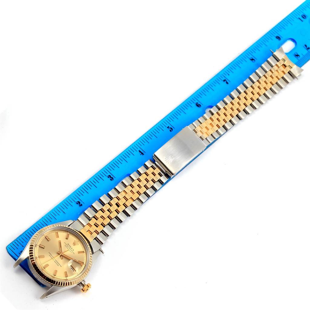 The Rolex Vintage Collection 1601 Men's Stainless Steel Champagne Dial 1601 Men's Stainless Steel Champagne Dial watch is displayed flat with a blue ruler, showing the watch face and gold and silver bracelet.