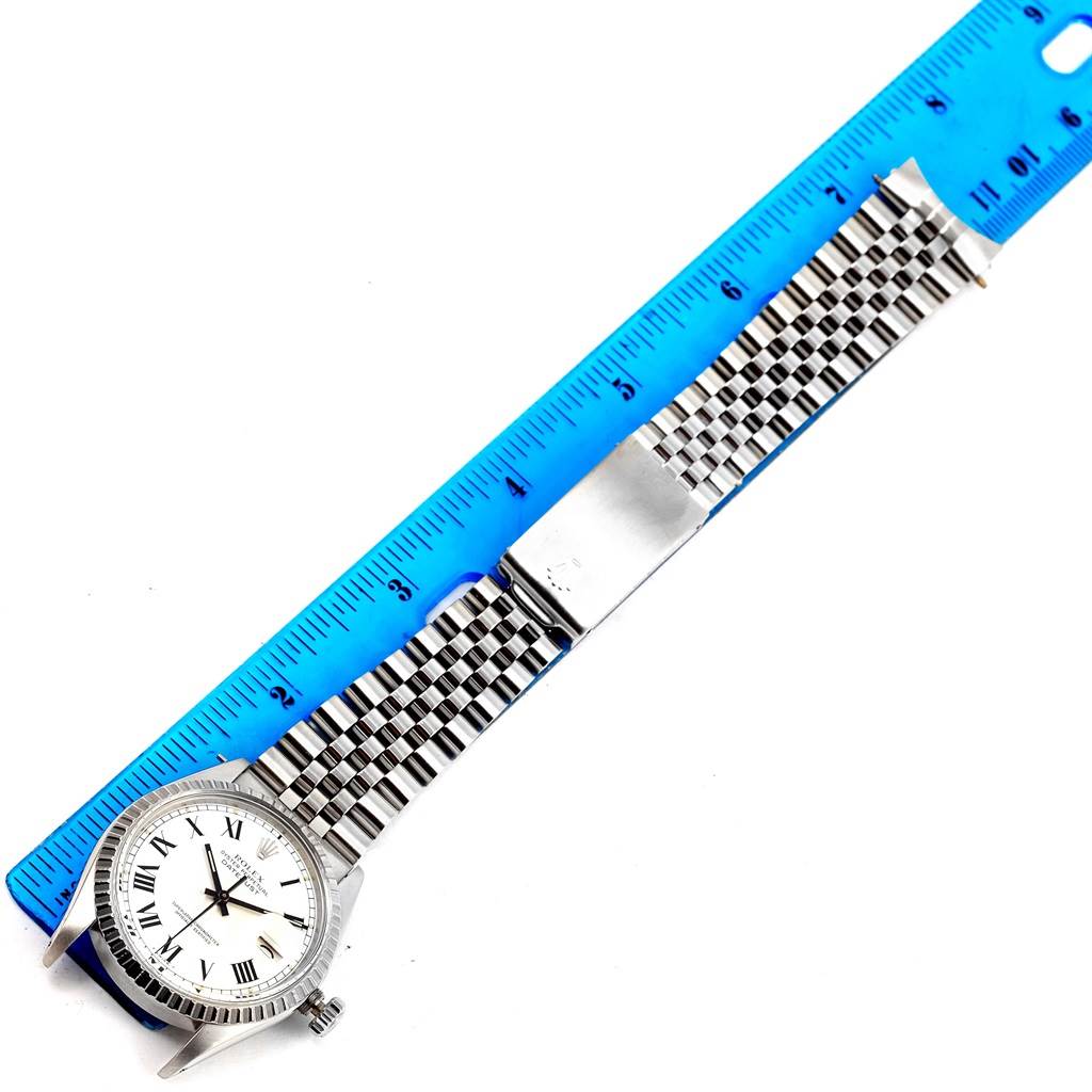 The Vintage Collection Rolex watch is shown flat, displaying its face and full metal bracelet alongside a ruler.