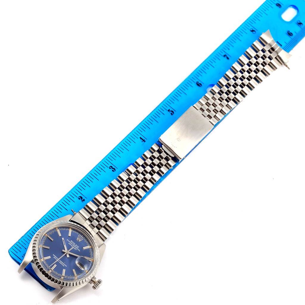 The image shows a Rolex Vintage Collection 1603 Men's Stainless Steel Blue Dial 1603 Men's Stainless Steel Blue Dial watch with a blue dial and jubilee bracelet measured against a blue ruler.